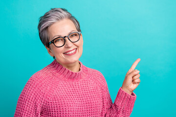 Portrait of optimistic senior woman wear pink pullover in eyewear indicating at offer empty space...