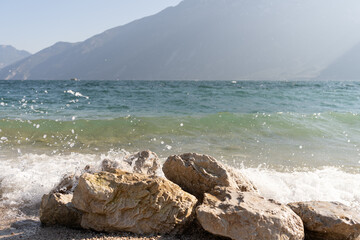 stones on the shore of a lake on a sunny day with mountains in the background