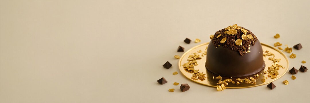 Chocolate truffles on golden plate with chocolate pieces and chocolate pieces on beige background