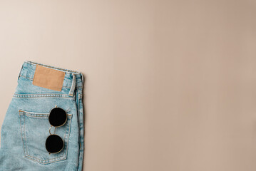 Sunglasses sticking out of jeans pocket on beige background