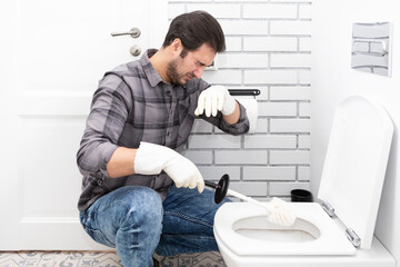 Сlose-up shot of a frustrated man cleaning a toilet using a special cleaning product and a brush