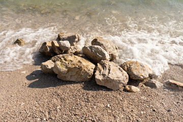 Fototapeta na wymiar a pile of stones on the shore of the beach that are washed by the sea water 