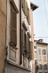 section of an old tenement  house in beige color with wooden shutters on a sunny morning in Italy
