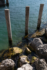 mooring posts on the embankment of a clear lake on a sunny day