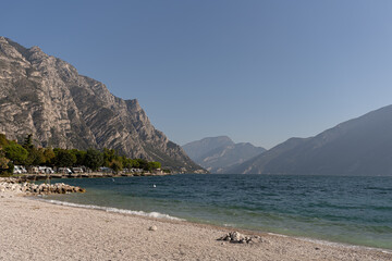 Lake Garda with a beach overlooking the mountains on a sunny day