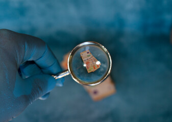 hand magnifying glass on 1000 peso bills, marking the devaluation of the Argentine currency