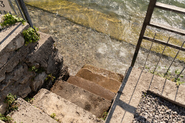 old, stone steps into the clear water of lake 