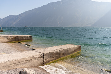 Lake Garda with a beach overlooking the mountains on a sunny day 