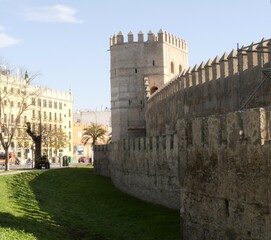 11th century fortified wall and watchtower alongside city buildings in Seville