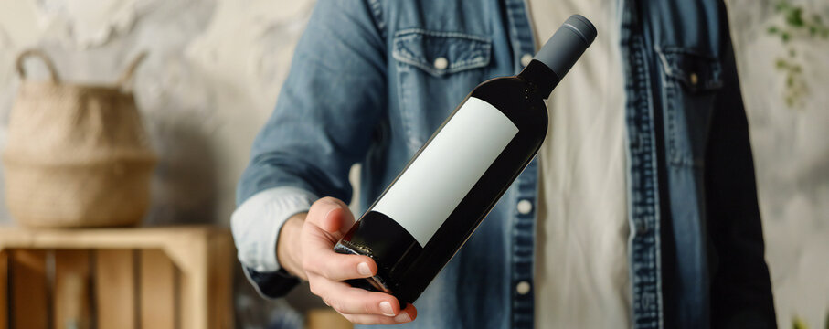 Man holding a bottle of wine with a label mockup