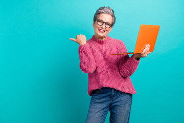 Portrait of nice woman wear pink pullover in eyewear hold laptop indicating at discount empty space isolated on turquoise color background