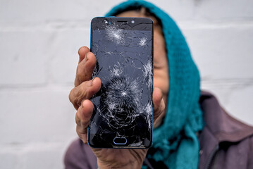 Broken glass screen smartphone in hand of senior woman.