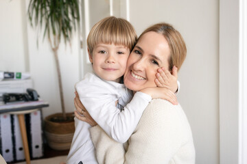 Happy young mother and little son having fun on cozy couch in living room, overjoyed mum and preschool child tickling, cuddling, enjoying leisure time together at home