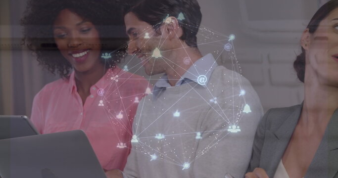 Image of globe of digital icons over mid section of diverse colleagues using electronic devices