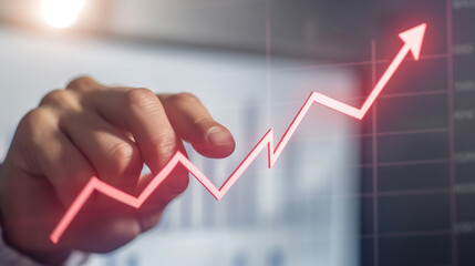 Person hand pointing at an increasing stock market or financial graph
