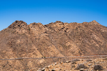 Fototapeta na wymiar View of a rocky mountain where a county road runs. Photography taken in Fuerteventura, Canary Islands, Spain.