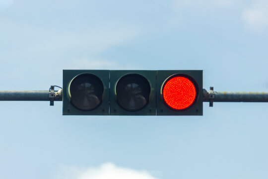 Red traffic light turns on, isolated on sky background