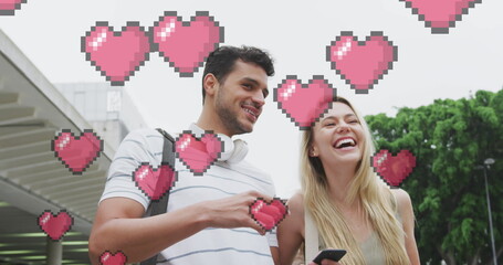 Image of heart icons floating over happy caucasian couple talking and using smartphone