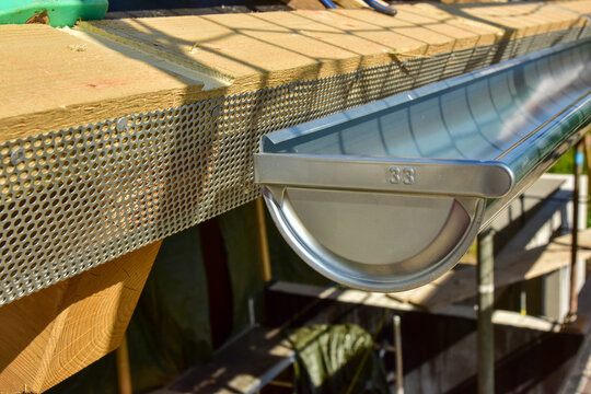 Montage des Lüftungsprofils am Trauf des Steildachs eines Holzhauses durch den Dachdecker