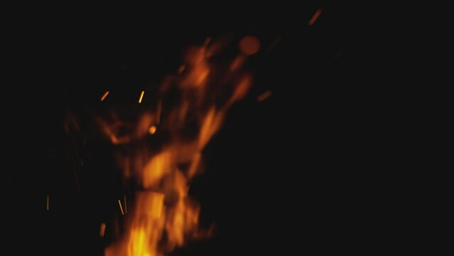 Fire embers particles over red smoke on black background. Abstract dark glitter fire particles lights. Bonfire in motion blur.