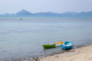 selective focus Two plastic kayang boats on the sandy beach on the island The sea water is clear during the summer. There is space for text.