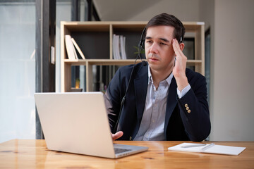 Stressed and tired Asian customer support agent or call center agent sitting at desk He has a headache or is overworked. and feel stressed by complaints from customers