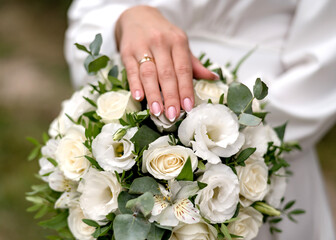 Obraz na płótnie Canvas The bride holds a bouquet of white roses