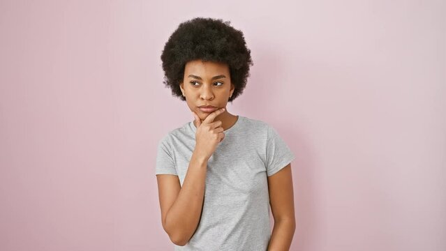 Pensive african american woman in pink tee, focused, finger on chin digesting doubt, lost in thought, standing isolated against pink background