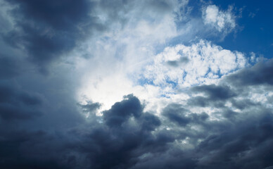 Naklejka na ściany i meble The sun is shining behind the rain cumulus clouds high in the sky