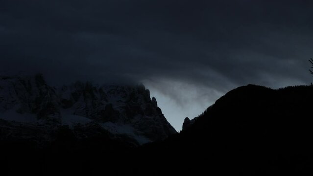 breve ripresa video timelapse che mostra la fase di transizione dalle ultime luci del tramonto alla prima fase di buio, in un ambiente di montagna, mentre le nuvole si spostano lungo un monte