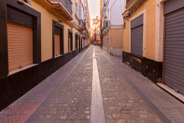Fototapeta na wymiar Old narrow traditional street in Cadiz at dawn.