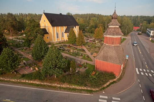 Aerial view of old yellow wooden church of Pusula and red bell tower, which represents neo-gothic style, surrounded with graveyard, Nummi-Pusula, Finland.