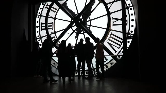Tourists standing in front of large clock, Paris, France. Unrecognizable people overlooking Paris.