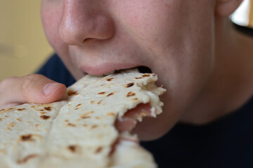 Closeup of a Boy's Mouth Eating a Flat Bread Filled with Cheese and Ham
