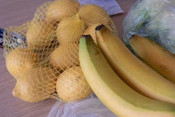 Bunch of Ripe Yellow Bananas Just taken out of the Grocery Bag Close to a Package of Lemons.