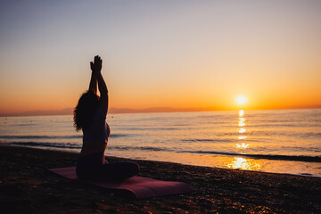 Carefree woman yoga practicing by the sea sunrise time