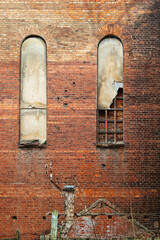 Tall arched windows in the facade of a brick wall of an old building