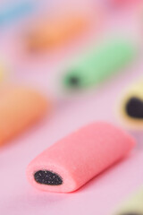 Multicolored chewing candies with licorice on a pink background. Swedish candy. Gummy candy pattern. Vertical orientation.