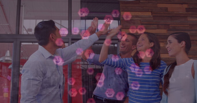 Image of icons floating over happy diverse coworkers clapping hands in office - Powered by Adobe