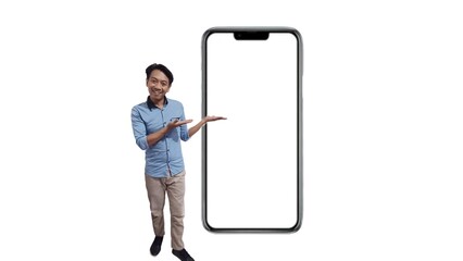 Full size asian young man in blue shirt sitting near big blank screen mobile phone with mockup area using smart phone isolated on plain white background