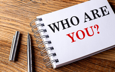 WHO ARE YOU text on notebook with pen on wooden background