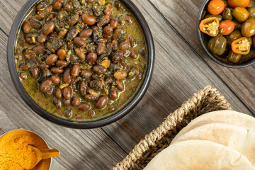 Black soybean curry.  Pickled chilies, turmeric, and a basket with some pita bread on the side.  
