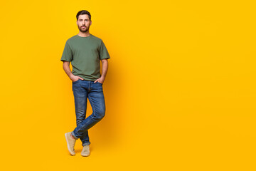 Fototapeta na wymiar Full length photo of attractive positive guy dressed green t-shirt walking empty space isolated yellow color background