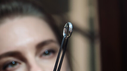Woman goldsmith looking at crafted silver ring. Jewelry handicraft. Close up