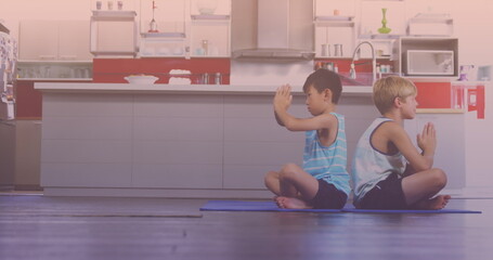 Asian and caucasian brothers performing yoga in the kitchen at home