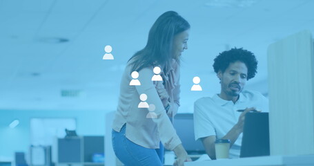 Image of social media user icons over diverse female and male coworkers in office