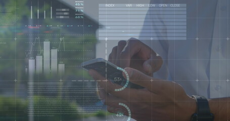Fototapeta premium Image of financial data and graphs over hands of african american man using smartphone