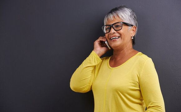 Glasses, phone call and senior woman in studio for communication, good news or gossip. Contact, mockup and elderly female person on mobile conversation with cellphone for talking by black background.