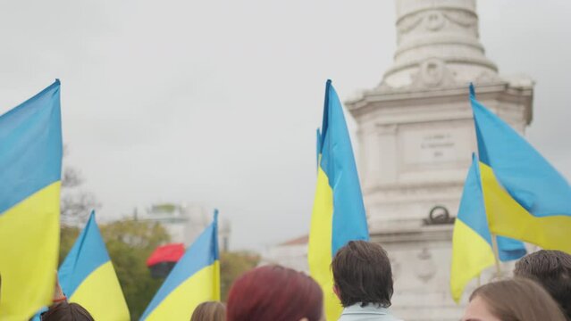 Ukrainian flag man and woman with blue yellow flags protest on the streets of Lisbon against war and and russian invasion in Ukraine. Support from European city to Ukraine