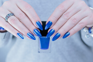 Woman's beautiful hand with long nails and bright blue manicure